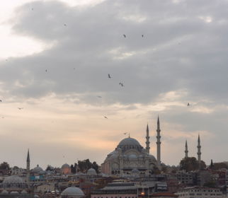 Wide view of the Bosphorus at golden hour with ferry traffic and the European shoreline glowing under amber light